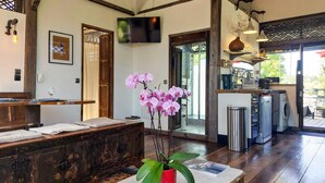 A hotel room with a wooden reception desk, a television mounted on the wall, a bathroom with a shower, and a dining area with a table and chairs. - Awesome home in Saint-Sulpice-de-Rouma (Saint-Sulpice-de-Rouma)