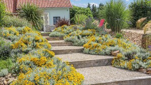 Un giardino con fiori gialli, una scala in pietra e un edificio con tetto in tegole rosse.