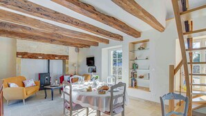 Un'area pranzo con tavolo apparecchiato per quattro persone, un divano, una televisione e una libreria.