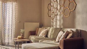 Quarto com sofá, mesa com vaso e luminária hexagonal fixada na parede.