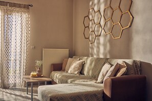 A room with a sofa, a table with a vase, and a wall-mounted hexagonal light fixture. - Pelagaki Sunrise Apartments (Zakynthos)
