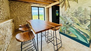 A rustic interior with a wooden table and bar stools, stone walls, and a mural of tropical scenery. - Le Belvédère du Quercy - Domaine Gouloumès (Soucirac)