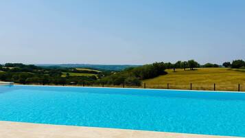 A swimming pool with a view of a green landscape and hills in the distance.
