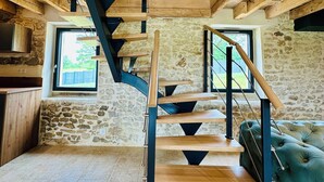 A wooden staircase with a black metal railing, leading to a room with a stone wall and a window. - Le Belvédère du Quercy - Domaine Gouloumès (Soucirac)