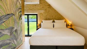 Une chambre avec un grand lit, un plafond en pente et une vue sur l’extérieur.