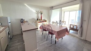 A modern kitchen with a dining area, a washing machine, and a large window. - CAP D'AGDE - Plage du Môle // Réf 0208 (CAP D'AGDE)