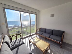 A balcony with a view of the ocean, a sofa, a chair, and a small table. - CAP D'AGDE - Plage du Môle // Réf 0208 (CAP D'AGDE)