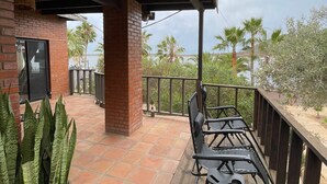 A covered patio area with a brick wall, a potted plant, and a table with chairs. - Hotel Molino Viejo  (San Quintín)