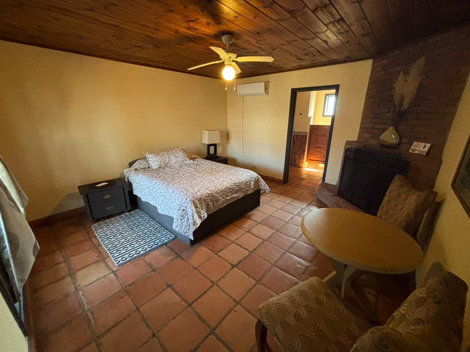 A bedroom with a bed, bedside tables, a ceiling fan, a small table, and a chair.
