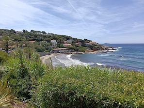 Un paisaje costero con playa, costa rocosa y edificios en una ladera.