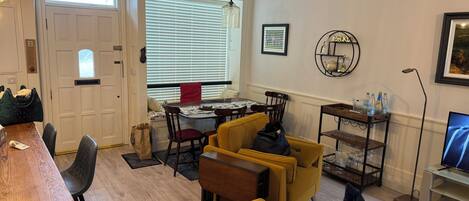 Un área de comedor con una mesa, sillas, un sofá, una mesa de centro y un televisor.