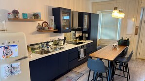 A modern kitchen with dark cabinetry, a wooden dining table, and a built-in oven.