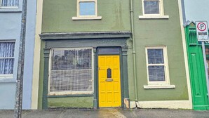 A row of colorful houses with a green house featuring a yellow door and a green gate.