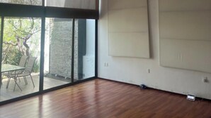 Ein geräumiges Zimmer mit großen Fenstern, Holzboden und einer Hängelampe.