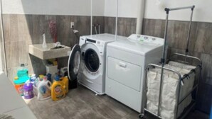 Ein Waschbereich mit Waschmaschine, Trockner und Wäscheständer.