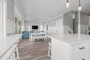 Een moderne keuken met witte kasten, een centraal eiland en een eethoek met een blauwe bank.