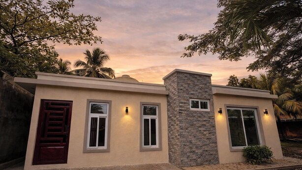 A modern house with a flat roof, a stone chimney, and a front door with a window above it.