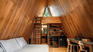Een gezellig, houten interieur met een hoogslaper, een bureau en een kitchenette.