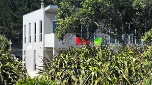 Um edifício moderno com telhado plano, grandes janelas e uma varanda.