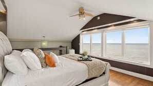A bedroom with a large bed, a ceiling fan, a view of the sea, and a window. - Waterfront | 4 guests | 1 bedroom | 2 beds | 2 full baths (Hilton)