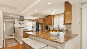 A modern kitchen with granite countertops, stainless steel appliances, and wooden cabinets. - Waterfront | 4 guests | 1 bedroom | 2 beds | 2 full baths (Hilton)