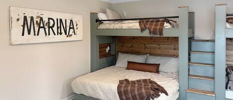 Una cama litera con cabecera de madera, un letrero en la pared y una escalera.