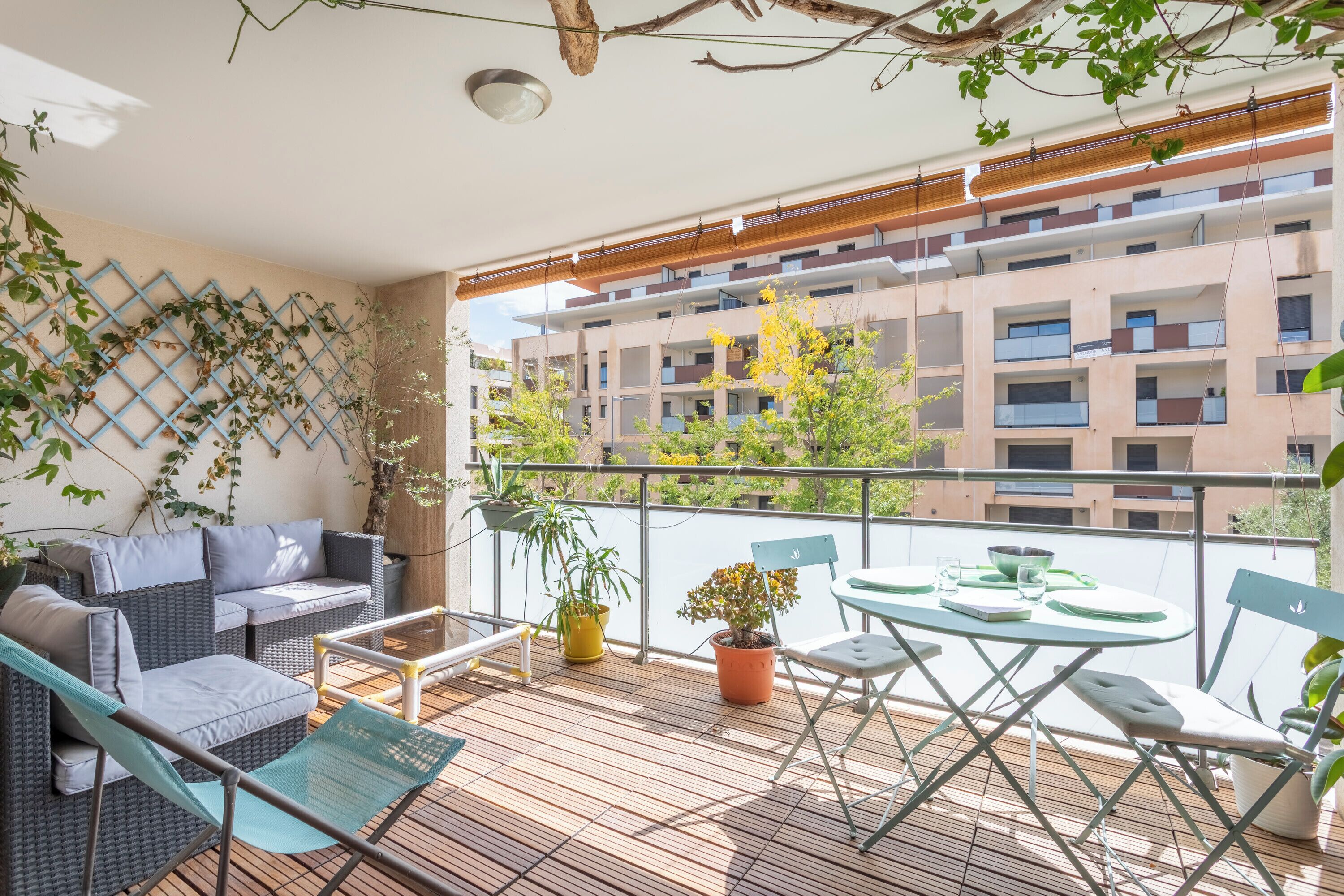 Ein Balkon mit einer Couch, Stühlen, einem Tisch und Topfpflanzen.