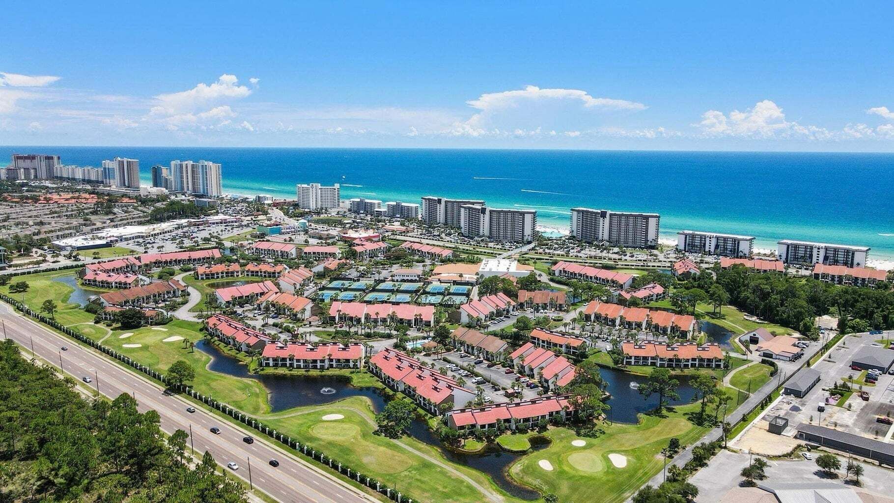 Ein Resort mit mehreren Gebäuden, einem Golfplatz und Blick auf den Ozean.
