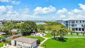 A coastal residential area with a view of the ocean, a tennis court, and a building with a flat roof. - 🦩Book Me Baby! Pinkie's Island Oasis🦩 (Destin)
