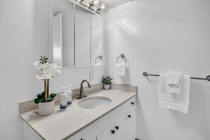 A bathroom with a sink, mirror, towel rack, and a potted plant. - New Listing! Steps to the beach in Kihei (Kihei)