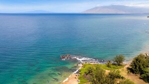 A coastal landscape with clear turquoise waters, a rocky shoreline, and a beach area with sparse vegetation. - New Listing! Steps to the beach in Kihei (Kihei)