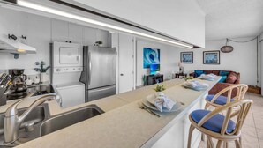 A modern kitchen with stainless steel appliances, a central island with seating, and a dining area with a sofa and chairs. - New Listing! Steps to the beach in Kihei (Kihei)