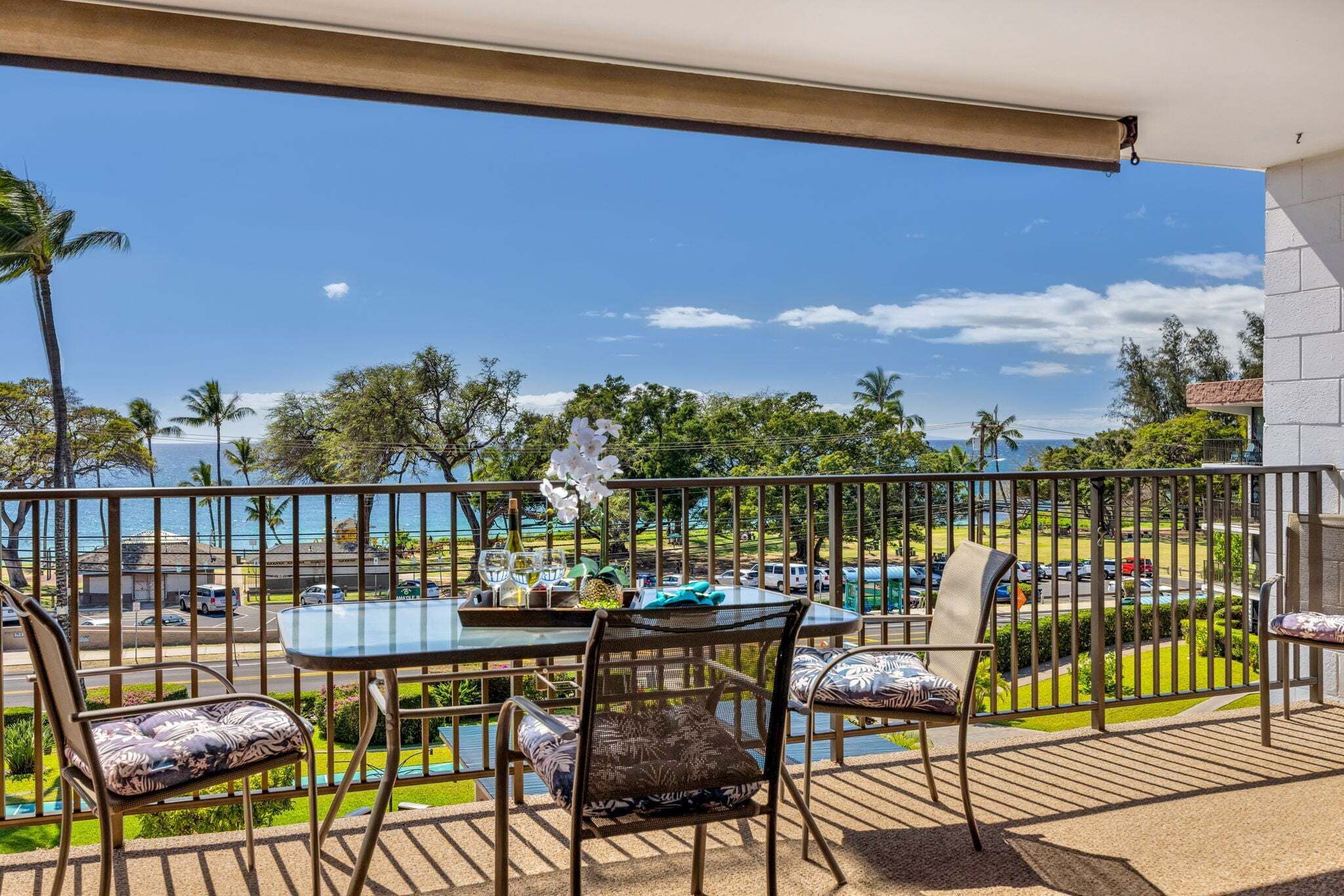 A balcony with a table and chairs, a view of the ocean, and a clear sky.
