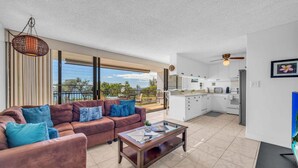 A modern living room with a sofa, coffee table, and a view of the balcony. - New Listing! Steps to the beach in Kihei (Kihei)