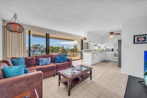 A modern living room with a sofa, coffee table, and a view of the balcony. - New Listing! Steps to the beach in Kihei (Kihei)