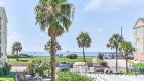 Uitzicht op de kust met palmbomen, een strand en een parkeerplaats met auto's.