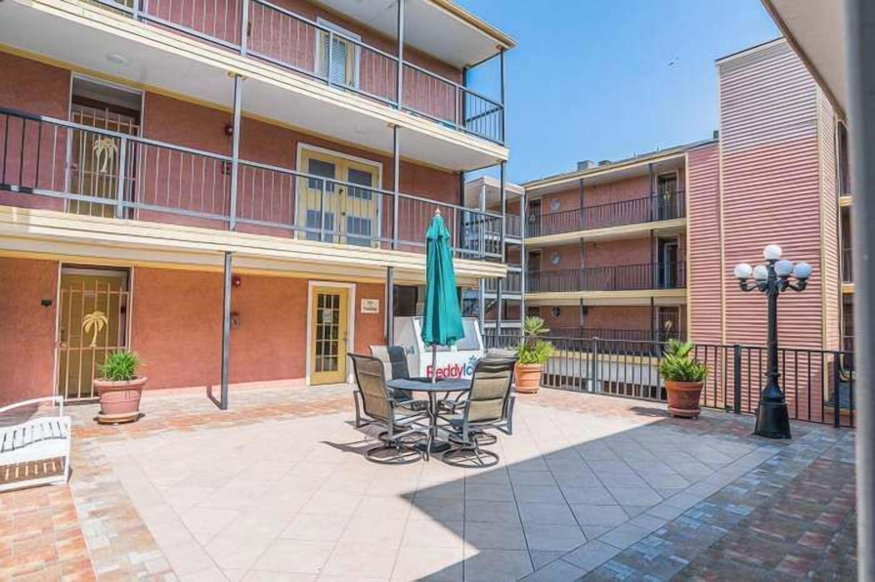 A multi-story building with balconies, outdoor seating, and potted plants.
