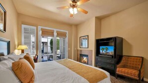 Une chambre d’hôtel avec un lit, une télévision, une cheminée et un fauteuil.