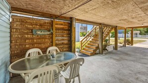 Un área de estar al aire libre con techo, mesa y sillas, paredes de madera y una escalera.