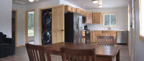 Una cocina compacta con armarios de madera, lavadora y secadora integradas, y un comedor con mesa y sillas.