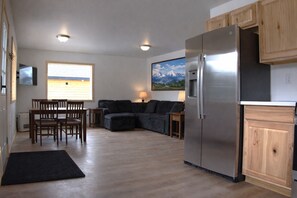 A compact kitchen with a built-in refrigerator, wooden cabinets, and a dining area with a table and chairs.