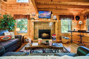 Un intérieur de chalet chaleureux avec une cheminée, des murs en bois, un téléviseur et un coin repas.