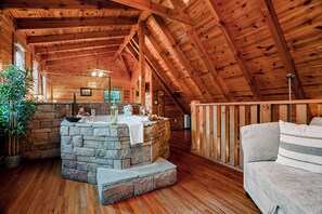 A cozy wooden interior with a stone fireplace, a wooden ceiling, and a cushioned seating area. - Couples Creekside Retreat w/ Hot Tub Near PF (Pigeon Forge)