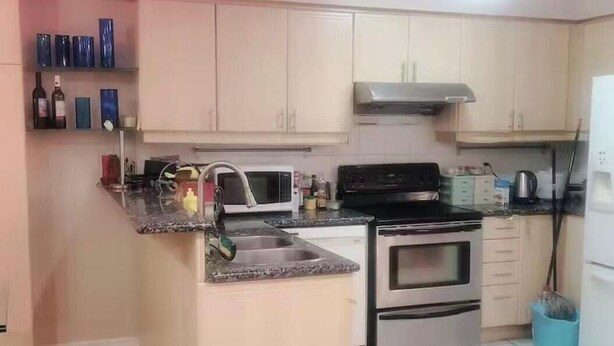 Une cuisine équipée d’un four à micro-ondes, d’une cuisinière, d’un évier et de placards.
