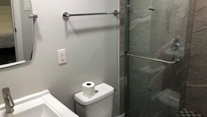 Une salle de bain avec un lavabo blanc, des toilettes et une douche à parois de verre.