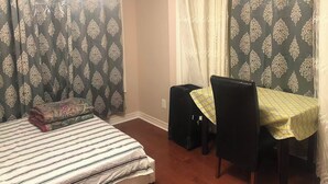 Une pièce avec un lit, une table recouverte d’une nappe jaune et une chaise.