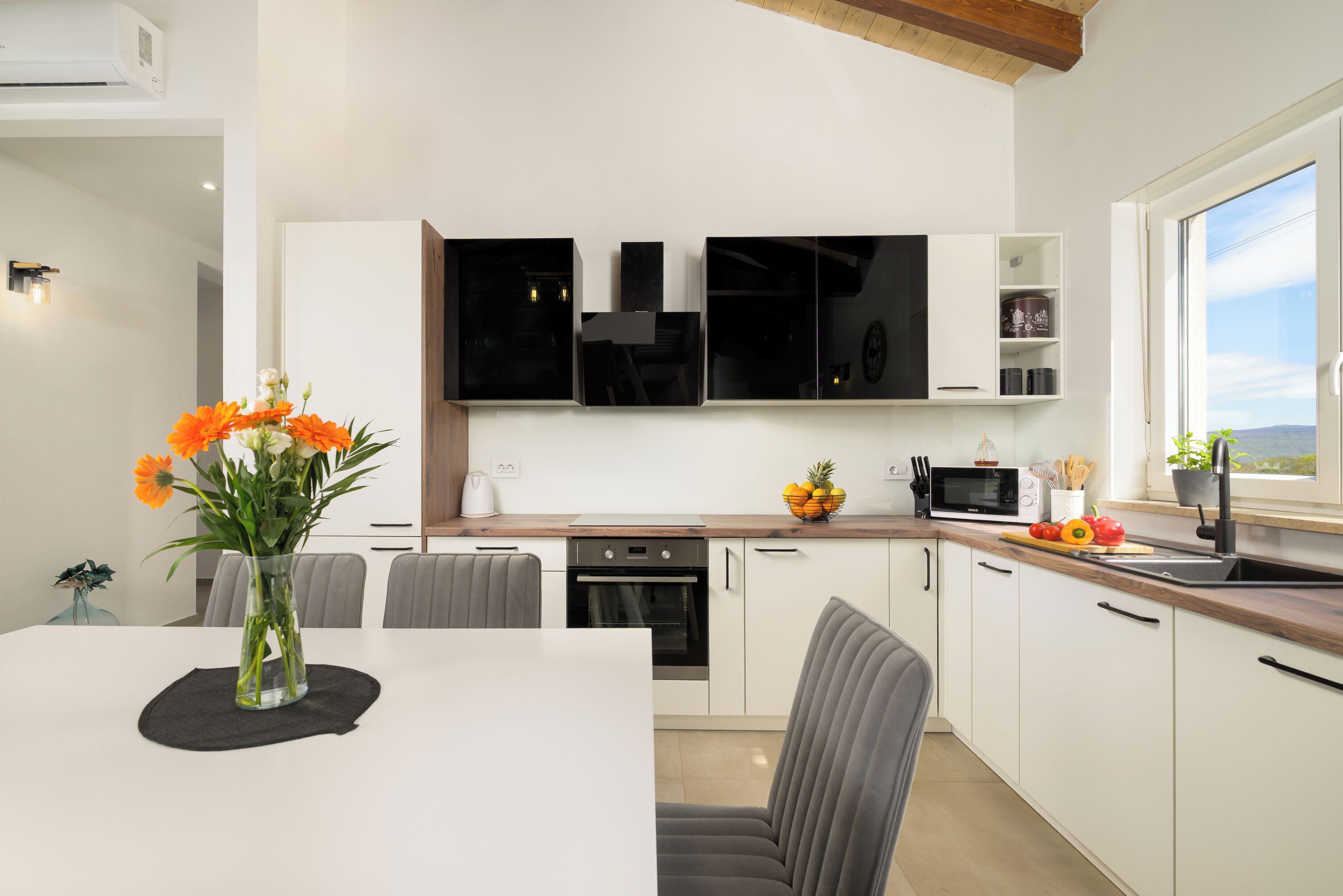 Une cuisine moderne avec des meubles blancs, un four à micro-ondes et un coin repas comprenant une table et des chaises.