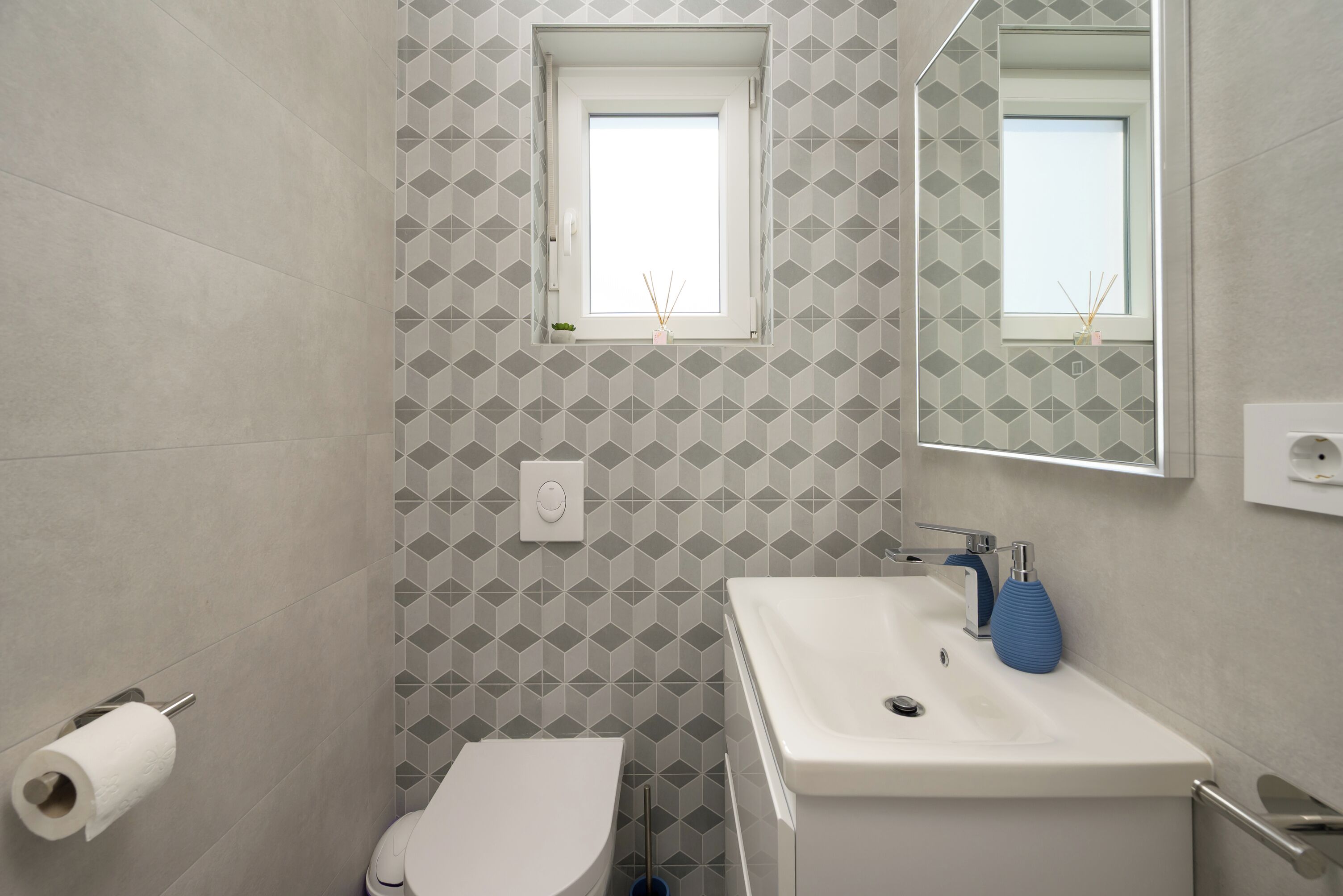 A bathroom with a toilet, sink, and a window with a view.