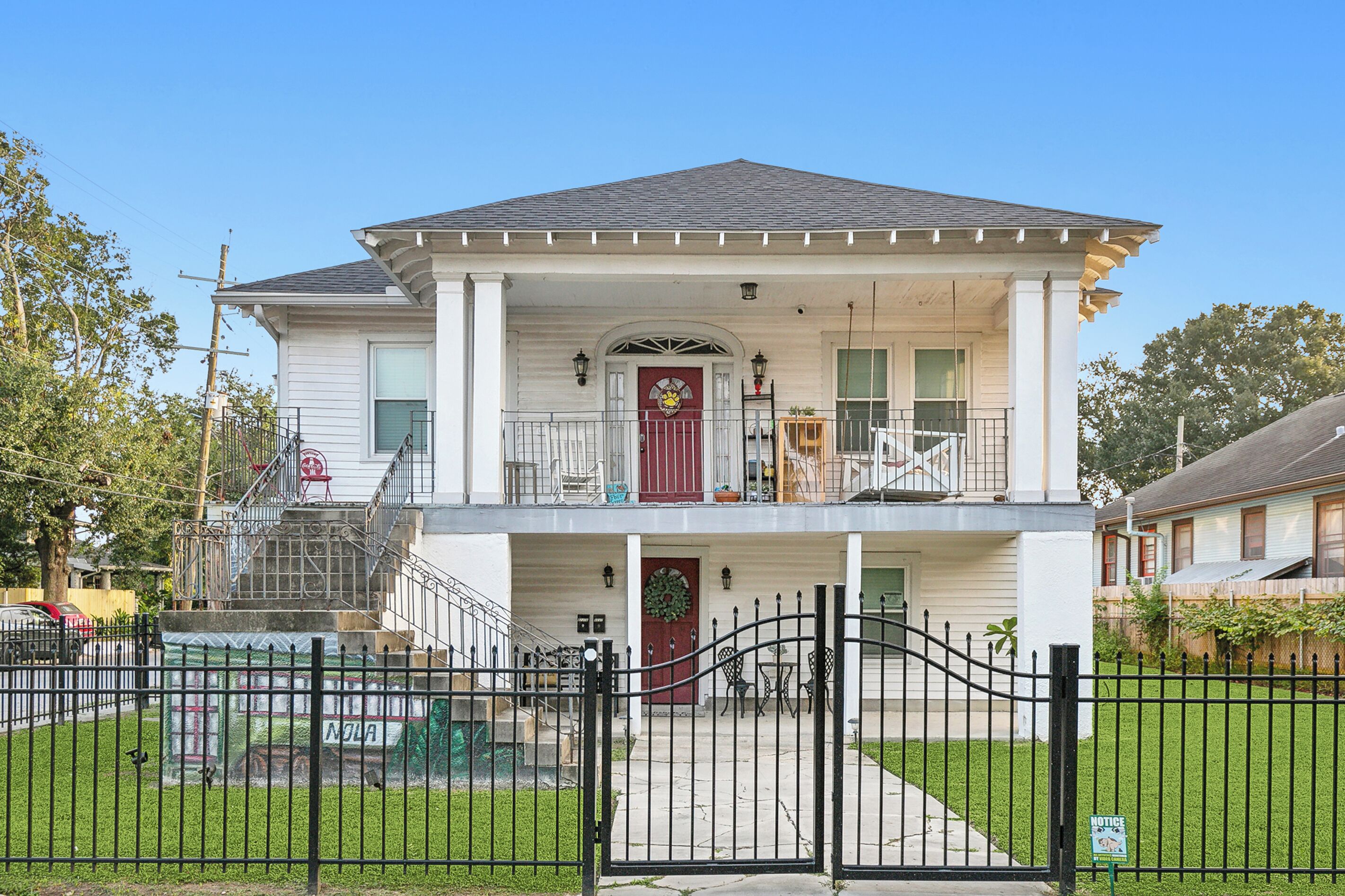 A two-story house with a front porch, a red door, and a staircase leading to the upper floor.