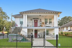 Une maison à deux étages avec un porche à l’avant, une porte rouge et un escalier menant à l’étage supérieur.
